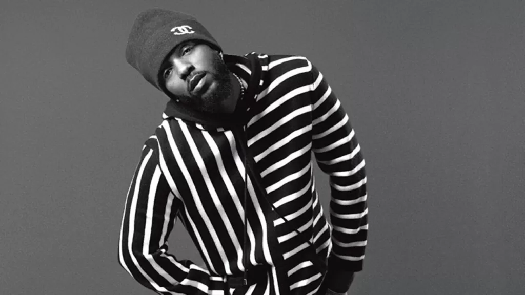 Cantor americano Kendrick Lamar vestindo um casaco listrado horizontalmente e touca