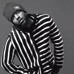 Cantor americano Kendrick Lamar vestindo um casaco listrado horizontalmente e touca