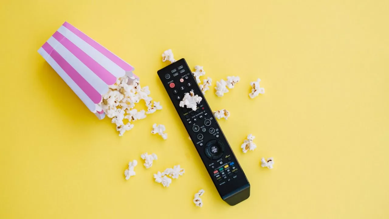 Imagem de um saco de pipoca espalhada e controle de TV