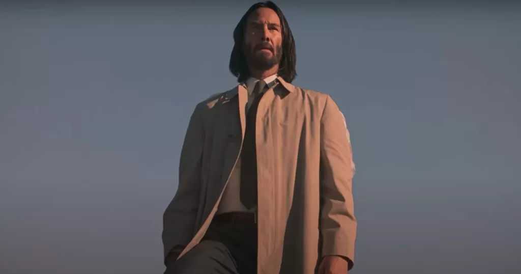 Keanu Reeves em pose contemplativa no filme "Quando o Céu se Engana", vestindo sobretudo claro sob o céu azul