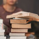 Pilha de livros sendo estudados por uma mulher