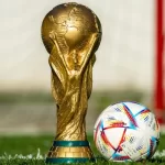 Taça da Copa do Mundo dourada com bola ao lado