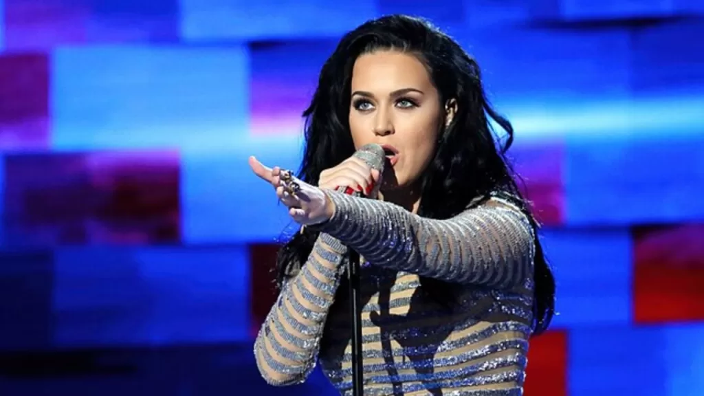 Katy Perry em show, com cabelos escuros e traje prateado